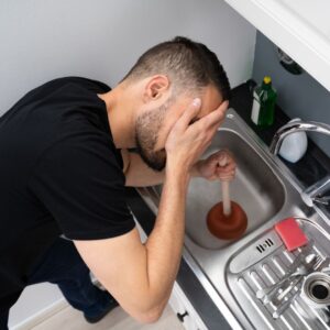 a person holding their head upset at a clogged sink