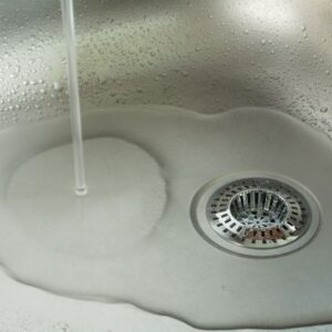 water running in a sink down a cleared drain