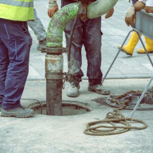 a team of workers putting a large pipe down a large sewer hole