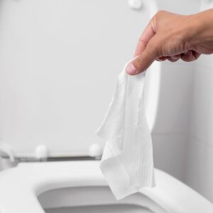 a person holding a wipe in front of an open toilet