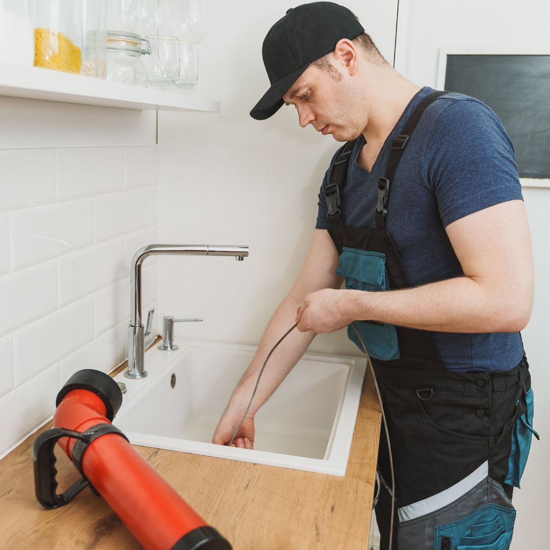 a worker putting a hose down a drain