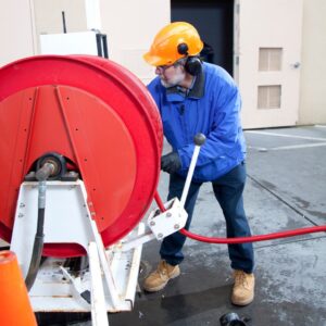 a worker in safety gear unwinding a long hose