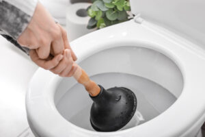 Person using a plunger on a toilet in Seattle, WA