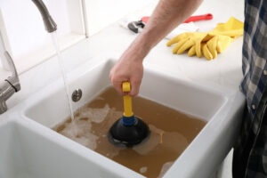 man using plunger to unclog sink drain in kitchen Bellevue, WA