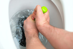 Person using a plunger on a clogged toilet Bellevue, WA